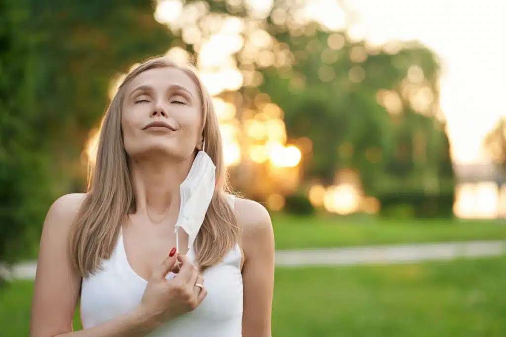 Woman taking off face mask, making deep breath.